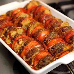 A scrumptious kofta bakes with slices of tomato and potato.
